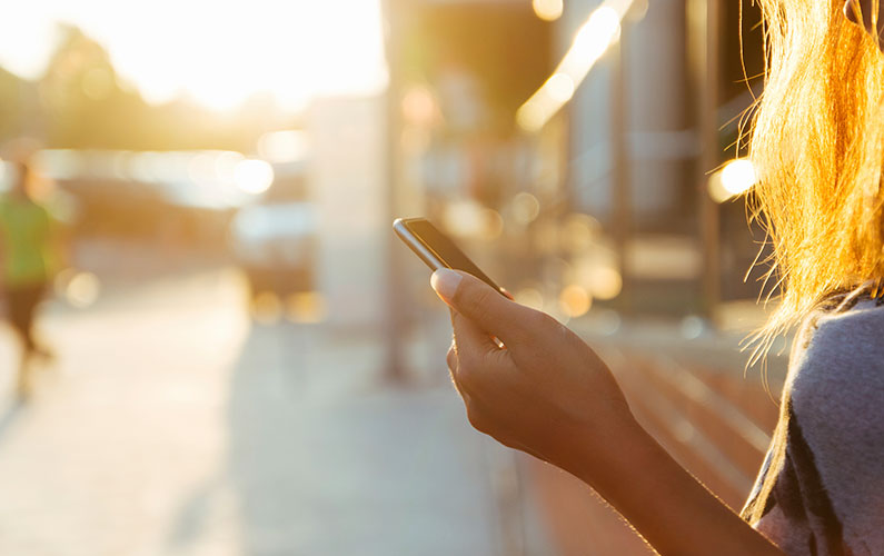 closeup of female student using smartphone for mobile banking at sunset